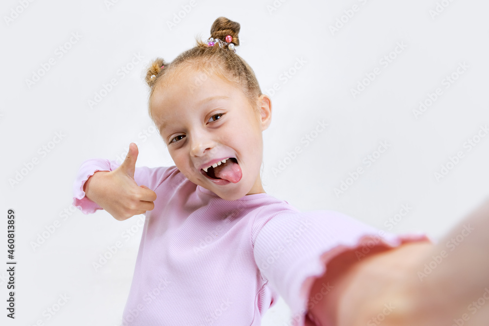 Close-up beautiful little smiling girl with buns on her head in modern stylish outfit looking at camera isolated on white studio background. Close-up beautiful little smiling girl with buns on her head in modern stylish outfit looking at camera isolated on white studio background.