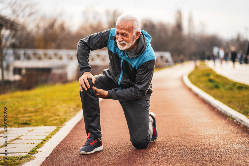 Active senior man is having pain in knee while jogging. - obrazy, fototapety, plakaty 