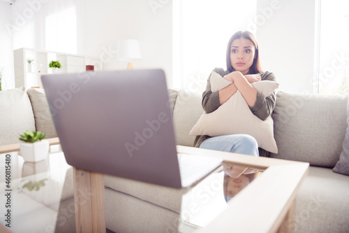 Photo of impressed shocked lady wear green shirt watching scary movie modern device embracing pillow copybook indoors room home