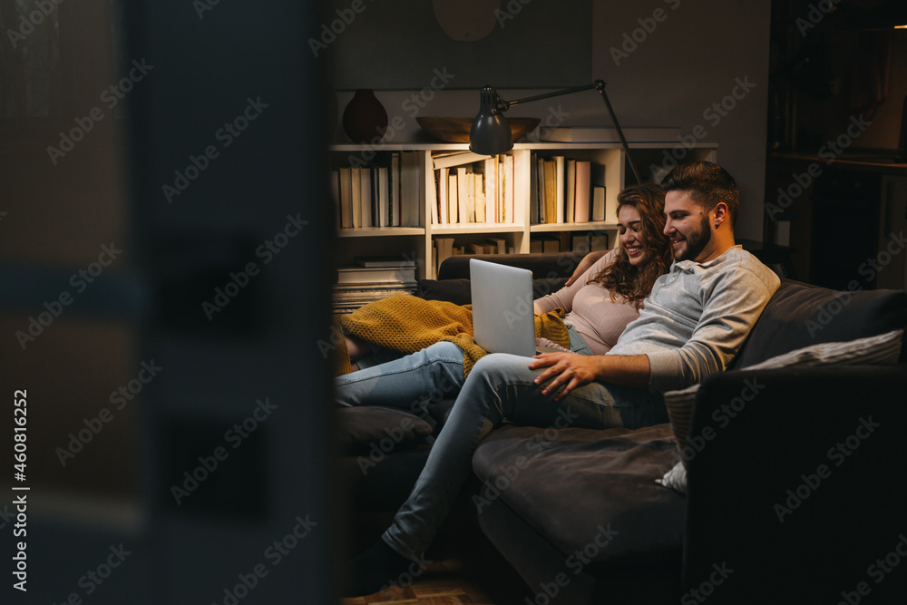happy young couple enjoying time at home using laptop computer