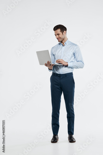 Smiling business man typing on laptop computer