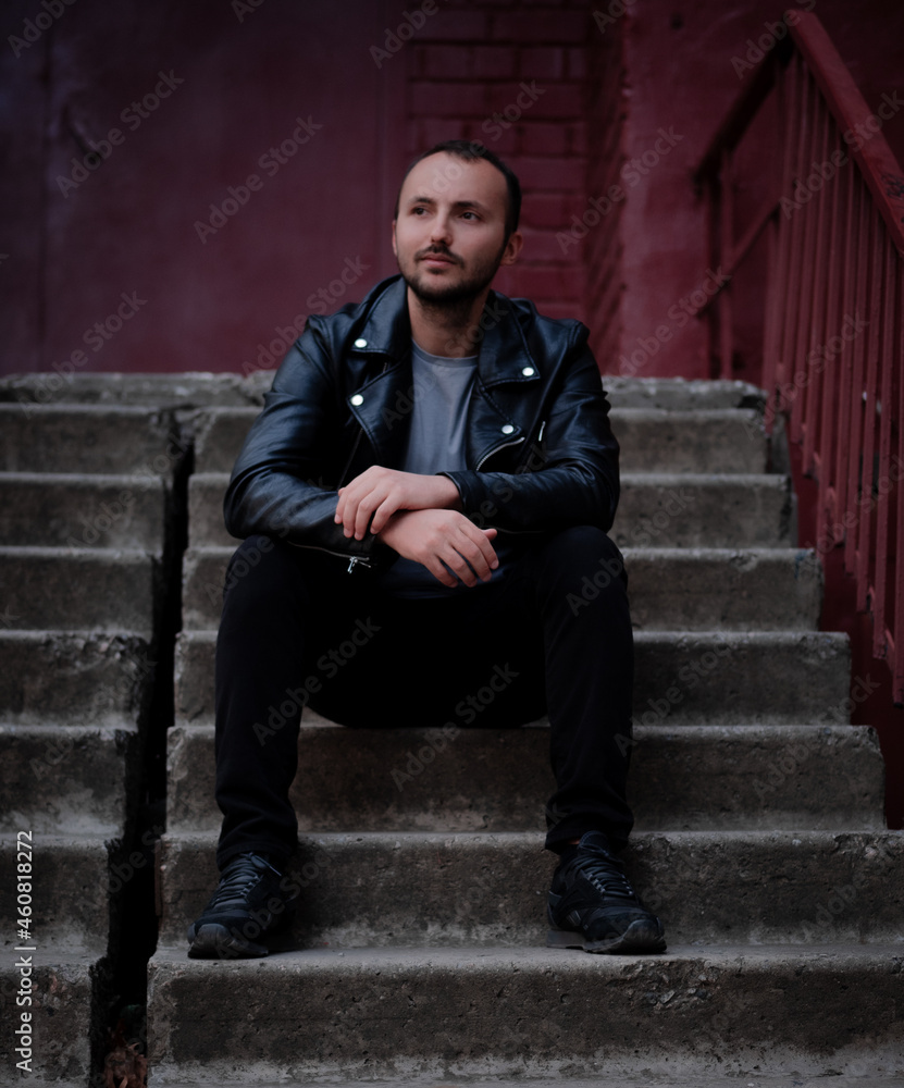 A man in a leather jacket sits on the steps A man in a leather jacket sits on the steps