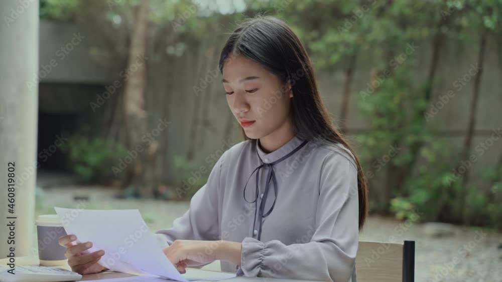 Asian businesswoman sitting outdoors working with laptop and documents.
Asian businesswoman sitting outdoors working with laptop and documents.