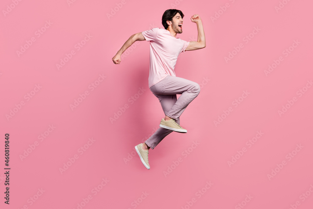 Full body profile side photo of young man happy positive smile jump up go walk run isolated over pink color background Full body profile side photo of young man happy positive smile jump up go walk run isolated over pink color background