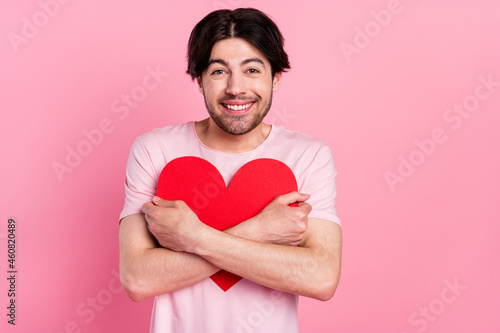 Photo of young man happy positive smile hug cuddle paper heart feelings romantic isolated over pink color background