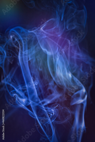 A vertical shot of smoke in colorfull backlight with a blue note