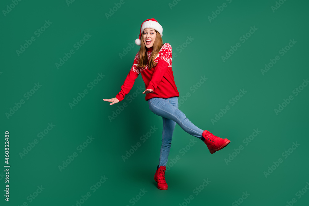 Full body photo of lovely young lady dance wear new year pullover cap jeans shoes isolated on green color background Full body photo of lovely young lady dance wear new year pullover cap jeans shoes isolated on green color background