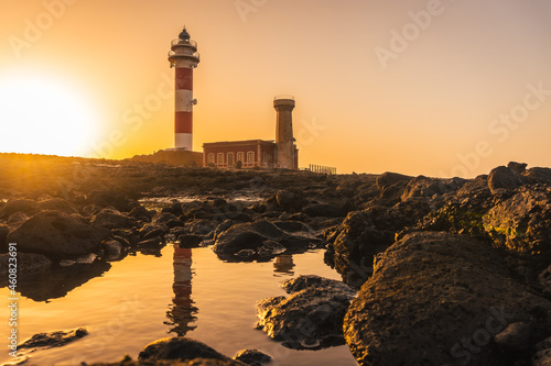 Sunset at the Toston Lighthouse near the sea with the reflected lighthouse, Punta Ballena near the town of El Cotillo, Fuerteventura island, Canary Islands. Spain
