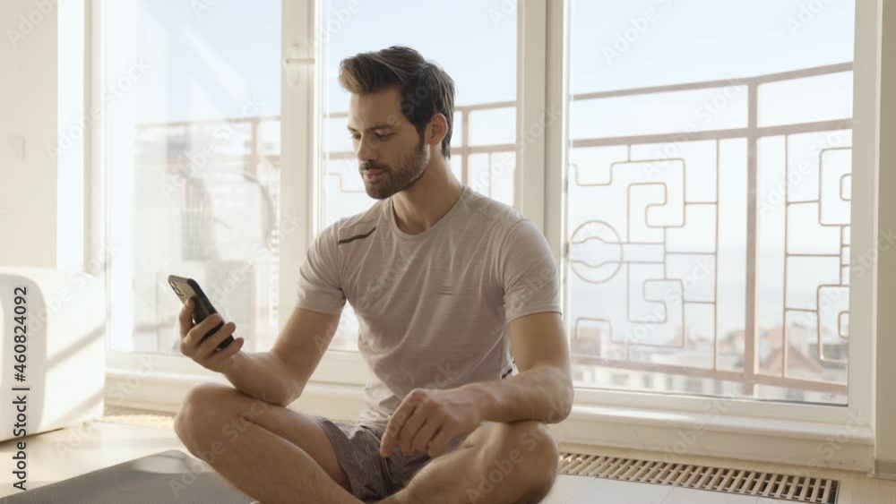 Confident man looking at the phone after training at home Confident man looking at the phone after training at home