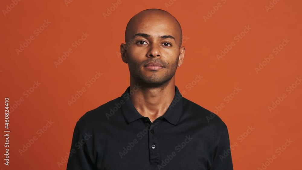 Positive bald Hispanic man agree with something in the orange studio Positive bald Hispanic man agree with something in the orange studio
