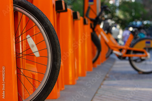 Wheel of bike on city orange parking station. Eco friendly transportation in urban area