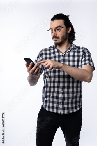 Portrait of young man with glasses using smartphone on white background. © daniromphoto