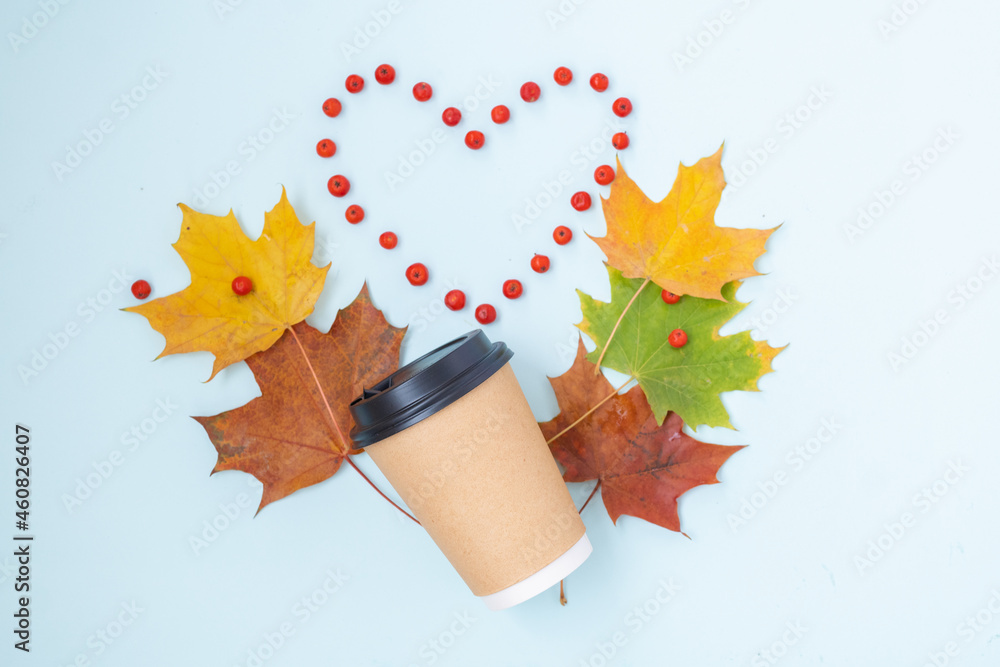 Flat lay of paper coffee cup with colorful autumn leaves, concept of coziness