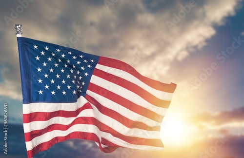 United States flag waving on the wind in front of sun and blue sky