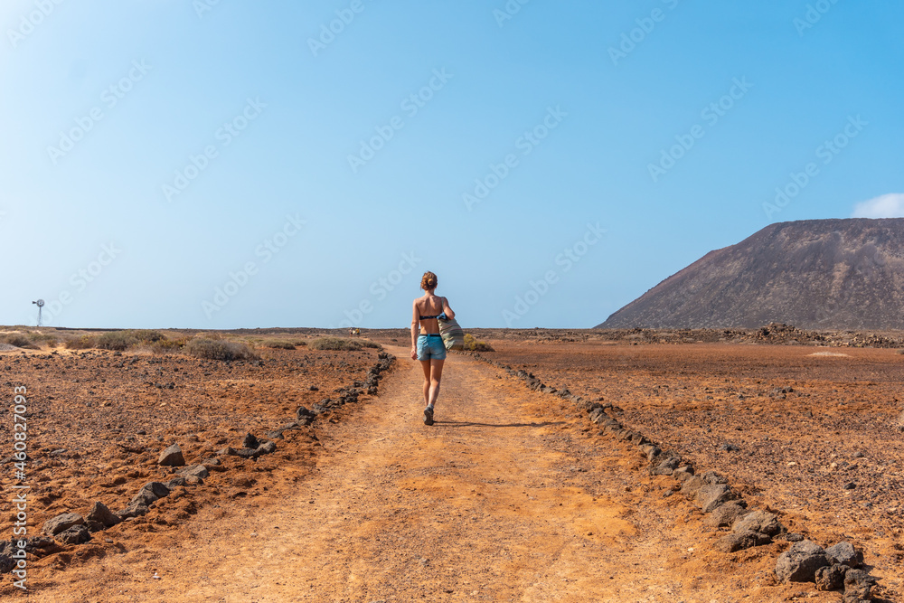 A young tourist girl walking the trails of Isla de Lobos, along the north coast of the island of Fuerteventura, Canary Islands. Spain