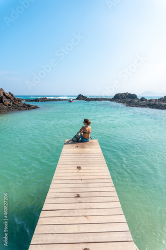 A young woman lying on the wooden walkway on Isla de Lobos, off the north coast of the island of Fuerteventura, Canary Islands. Spain