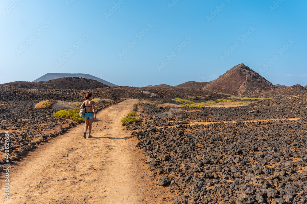 A young woman on the path to the north of the Isla de Lobos, along the north coast of the island of Fuerteventura, Canary Islands. Spain