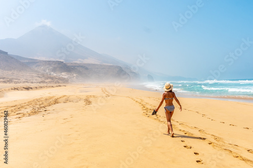 A young woman walking alone on the wild Cofete beach of the Jandia natural park  Barlovento coast  south of Fuerteventura  Canary Islands. Spain