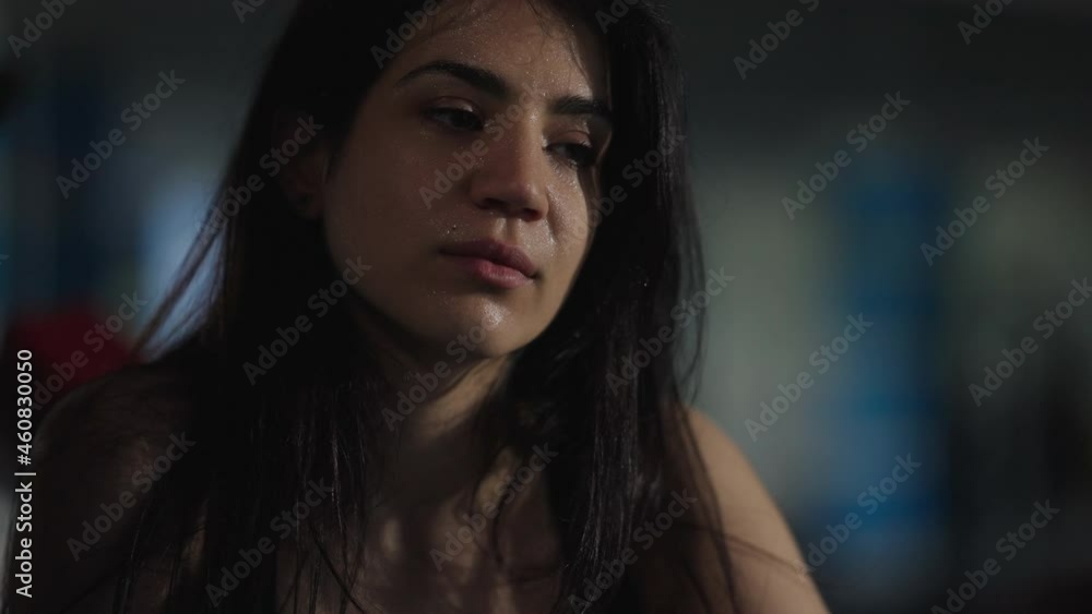 Close-up face of serious perspiring Middle Eastern sportswoman sighing in gym after training. Beautiful slim fit sportswoman bodybuilder resting after workout indoors. Confidence and motivation Close-up face of serious perspiring Middle Eastern sportswoman sighing in gym after training. Beautiful slim fit sportswoman bodybuilder resting after workout indoors. Confidence and motivation