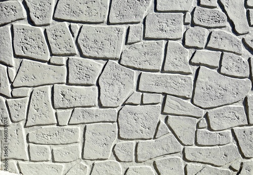 Gray concrete wall with forms of fake decorative rocks carved on the surface. Background and texture.