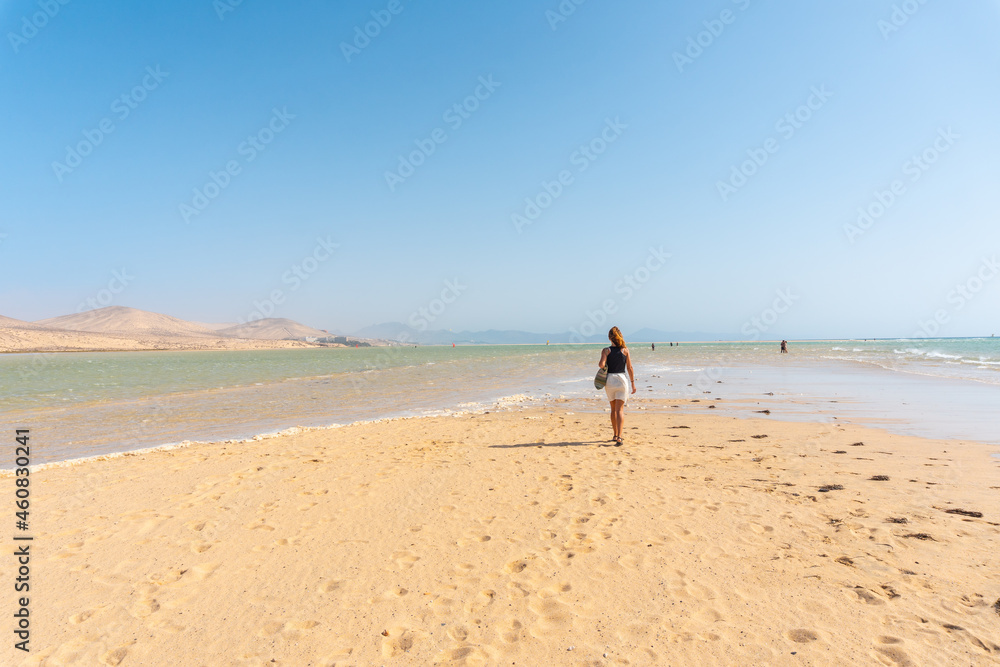 A young tourist walking along the Sotavento beach one autumn morning in the south of Fuerteventura, Canary Islands. Spain