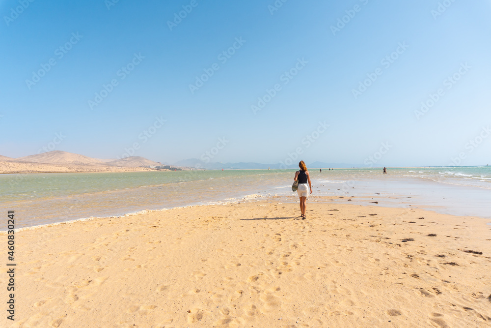 A young tourist walking along the Sotavento beach one autumn morning in the south of Fuerteventura, Canary Islands. Spain A young tourist walking along the Sotavento beach one autumn morning in the south of Fuerteventura, Canary Islands. Spain