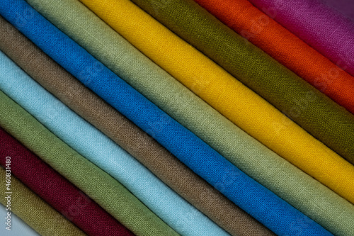 A stack of multi-colored bright linen fabric, close-up. Linen background. Fabric stripes