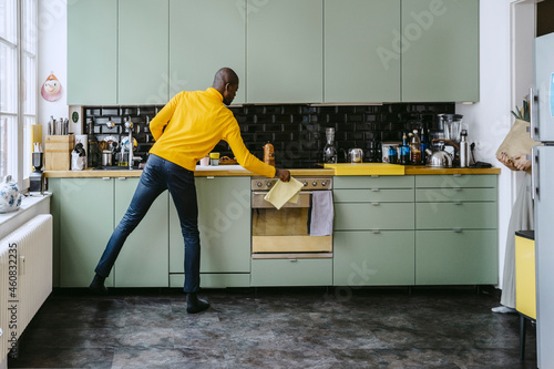 Full length of mid adult man doing chores in kitchen at home photo