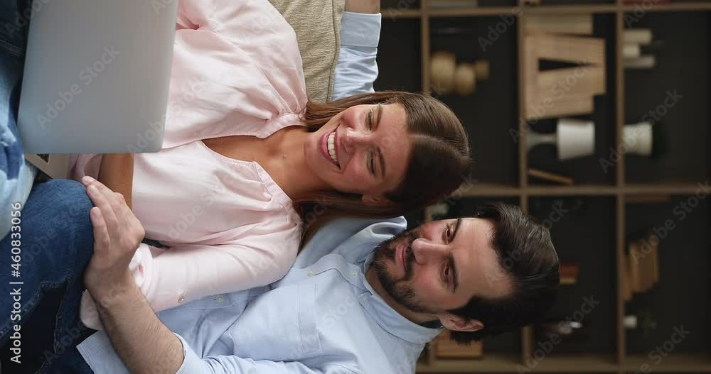 Interested millennial spouses couple in love rest on couch at home on weekend hold laptop use ecommerce web app to make purchases online. Bonding young husband wife enjoy watching video on computer Interested millennial spouses couple in love rest on couch at home on weekend hold laptop use ecommerce web app to make purchases online. Bonding young husband wife enjoy watching video on computer
