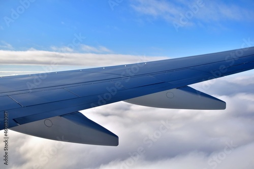 Wing of airplane. Wing of a passenger plane on background of blue sky above white fluffy clouds