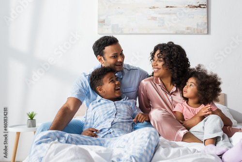 happy african american couple talking in bed near cheerful kids