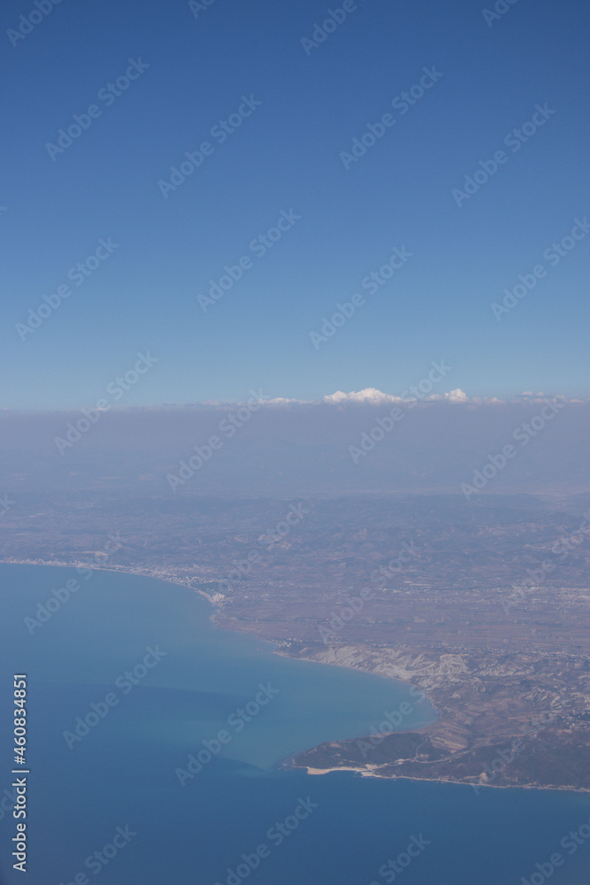 View from the plane. Natural landscape and cumulus clouds. Sea view from above. Beautiful blue sea and sky