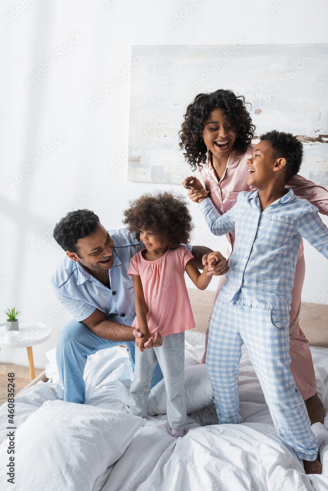 cheerful african american family holding hands and laughing in bed cheerful african american family holding hands and laughing in bed