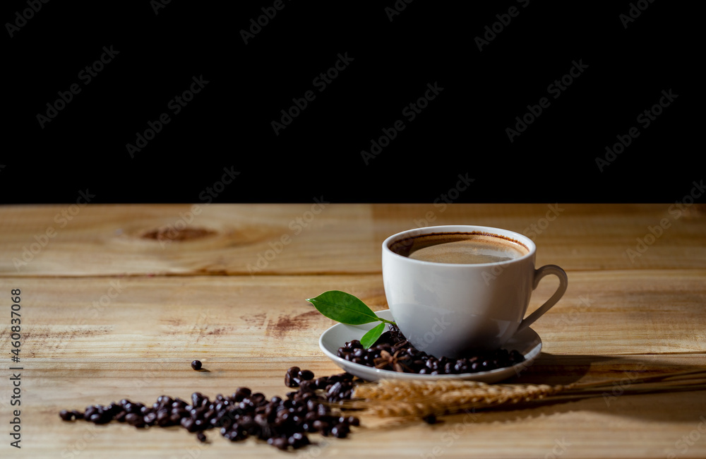 Hot cappuccino coffee in cup and beans with green leaf on wooden table at cafe. Dark scene and use for banner Hot cappuccino coffee in cup and beans with green leaf on wooden table at cafe. Dark scene and use for banner
