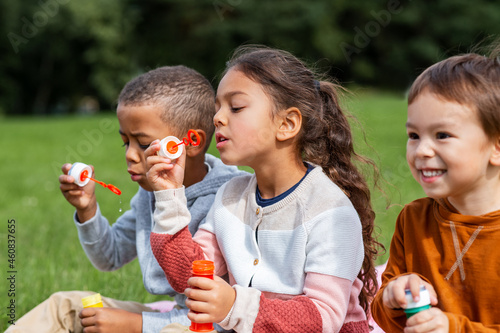 childhood, leisure and people concept - group of children blowing soap bubbles at park