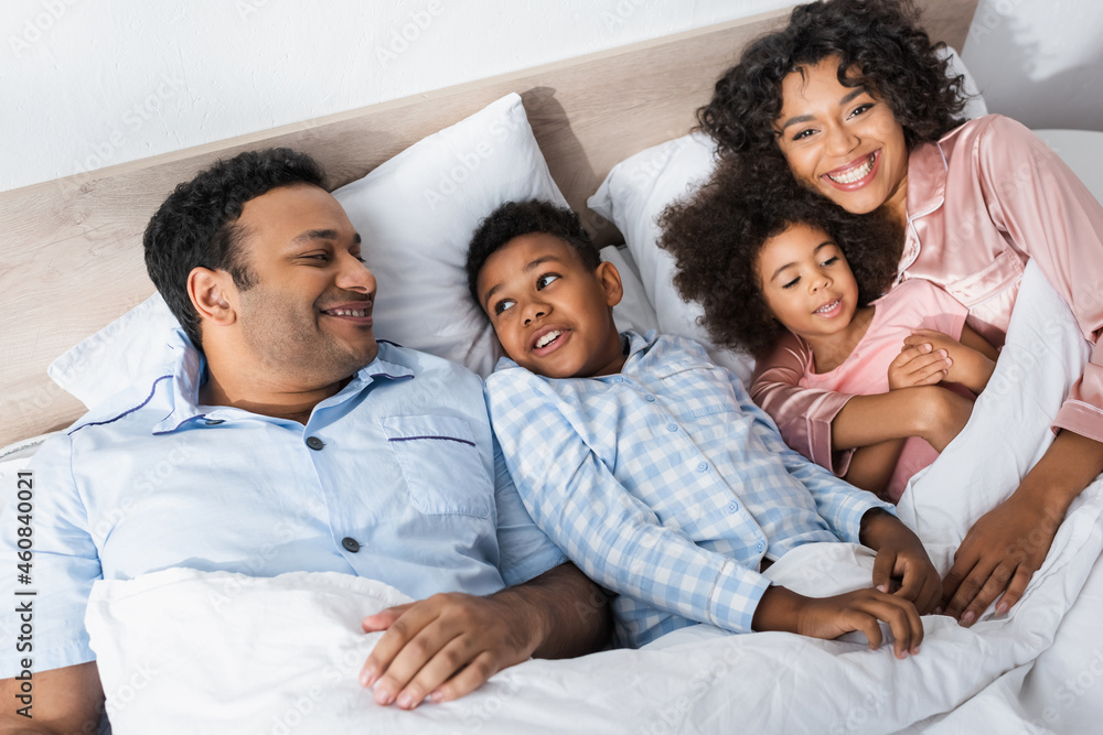 high angle view of cheerful african american family lying in bed in morning high angle view of cheerful african american family lying in bed in morning