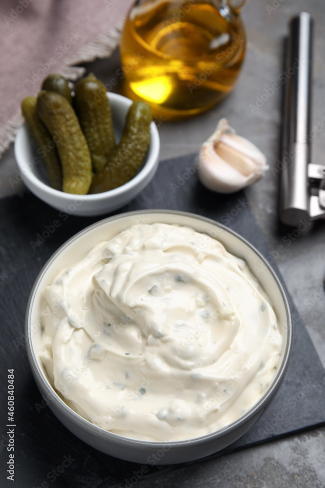 Tasty tartar sauce and ingredients on grey table Tasty tartar sauce and ingredients on grey table