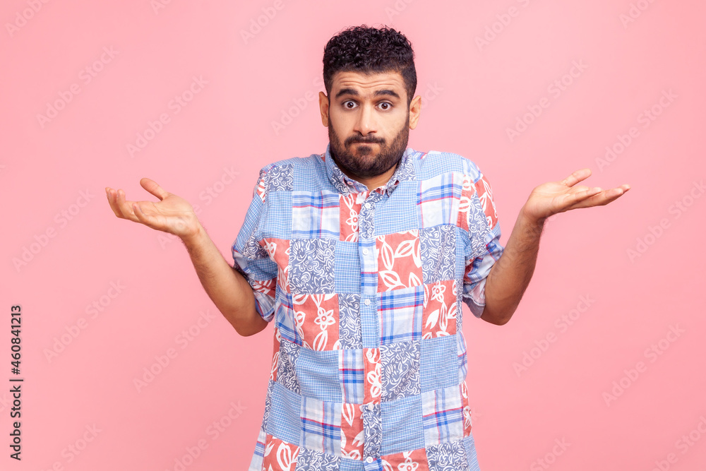 Portrait of clueless confused man in blue casual style shirt shrugging shoulders as doesn't know answer, can`t make decision, being uncertain, not sure. Indoor studio shot isolated on pink background. Portrait of clueless confused man in blue casual style shirt shrugging shoulders as doesn't know answer, can`t make decision, being uncertain, not sure. Indoor studio shot isolated on pink background.