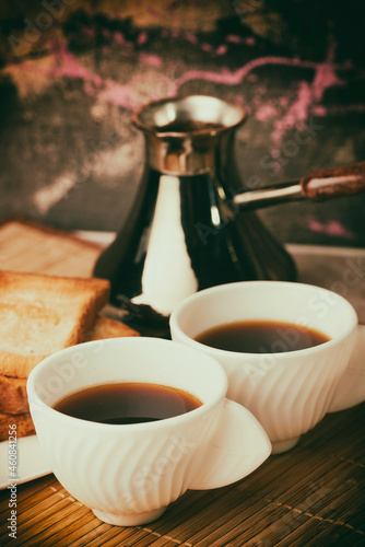 Coffee is poured into white cups. Toasted bread. Breakfast on the table. © sementinov