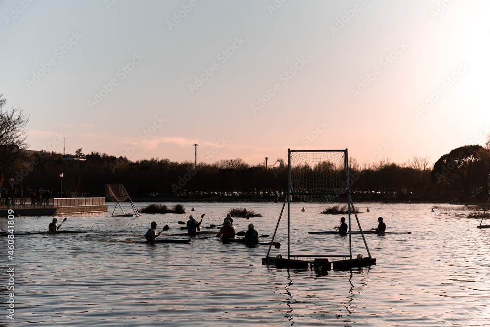 Silhouettes of people playing kayak polo during sunset
