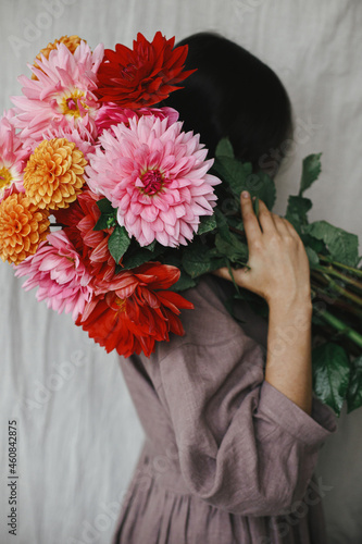 Fotografiet Beautiful woman holding colorful dahlias flowers in rustic room