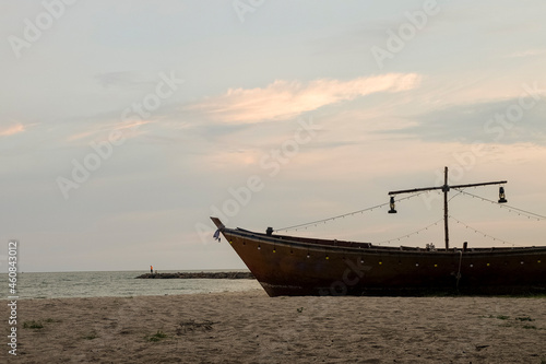 A fishing boat moored on the sandy beach in the morning. © Tanakit_Ktt