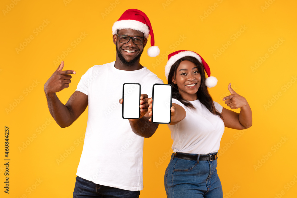 Black Couple Showing Phones Blank Screens Gesturing Thumbs-Up, Yellow Background
