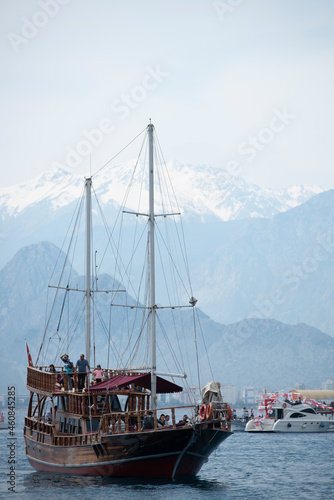 Tourist pleasure boats on the Mediterranean coast of Antalya with high snowy mountains in the background