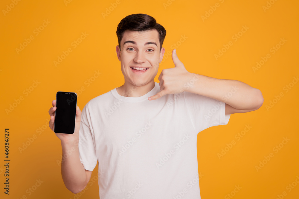 Portrait of reliable funny guy hold phone touch screen blank space show call me back sign on yellow background Portrait of reliable funny guy hold phone touch screen blank space show call me back sign on yellow background