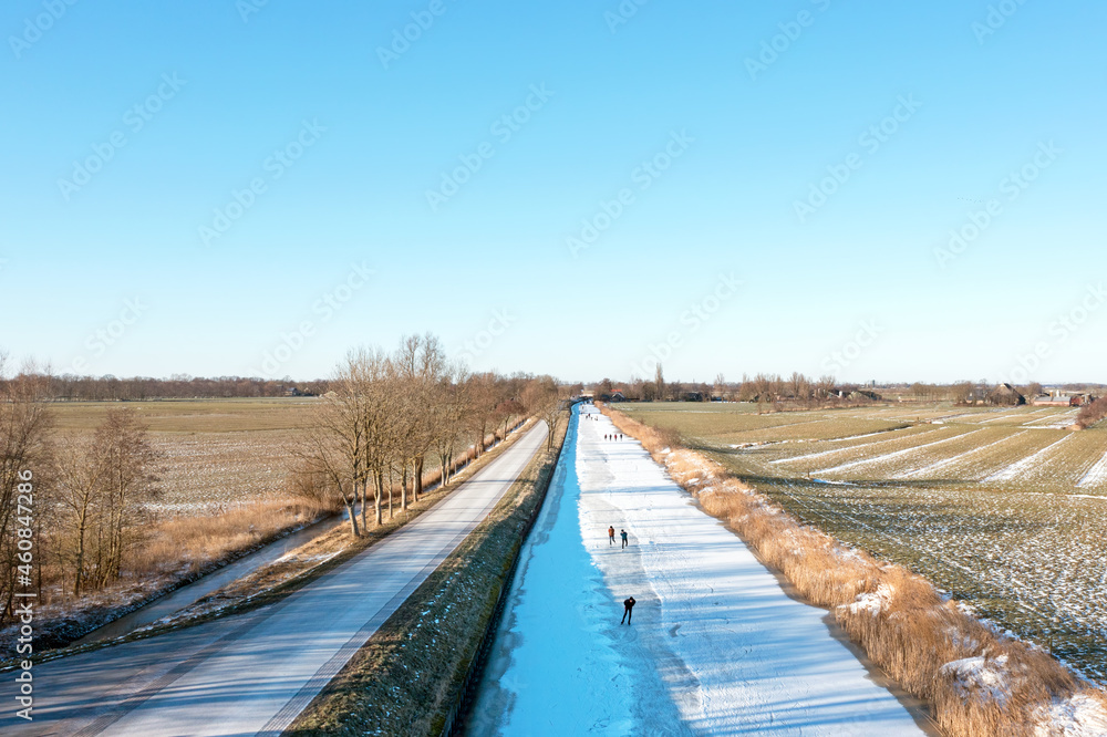 Aerial from ice skaters on a canal in the countryside from the Netherlands