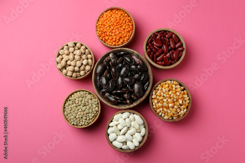 Flat lay composition with different types of beans on pink background