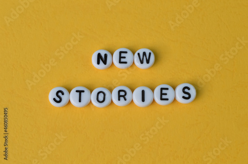 Alphabet beads with text NEW STORIES isolated on a yellow background