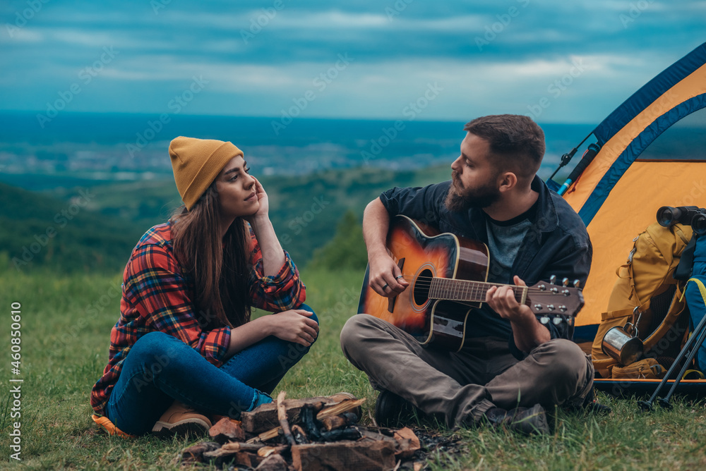 Couple of campers playing guitar and camping in the nature