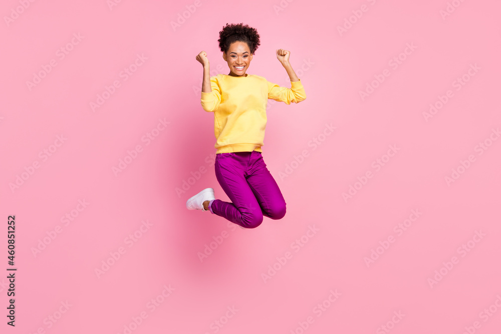 Photo of shiny beautiful woman dressed yellow sweater smiling jumping high rising fists isolated pink color background